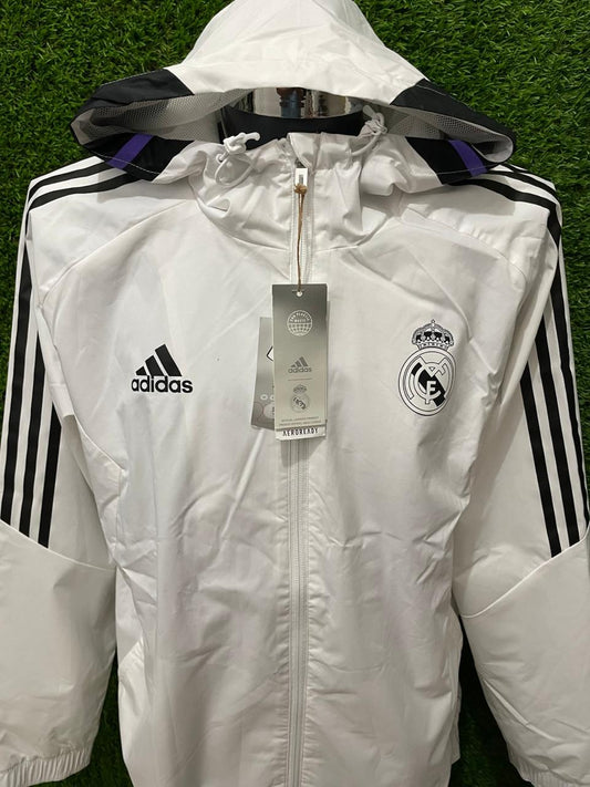 ROMPEVIENTOS REAL MADRID CON GORRO 2022